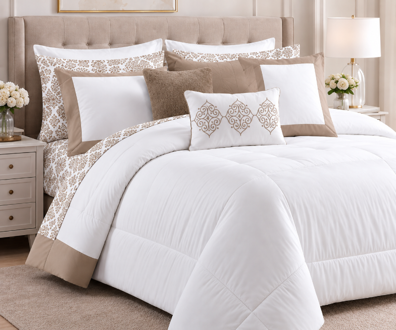 A neatly made bed dressed in a white comforter set with beige and taupe pillows, including a decorative lumbar pillow with an embroidered geometric pattern, set in a bright, modern bedroom.